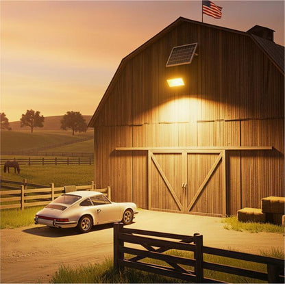 A high-brightness solar floodlight installed on a rustic wooden barn at dusk, effectively illuminating a white classic sports car parked below. The image showcases the powerful lighting coverage and the separate solar panel mounted above the light, demonstrating a practical security lighting solution for farms and rural properties.